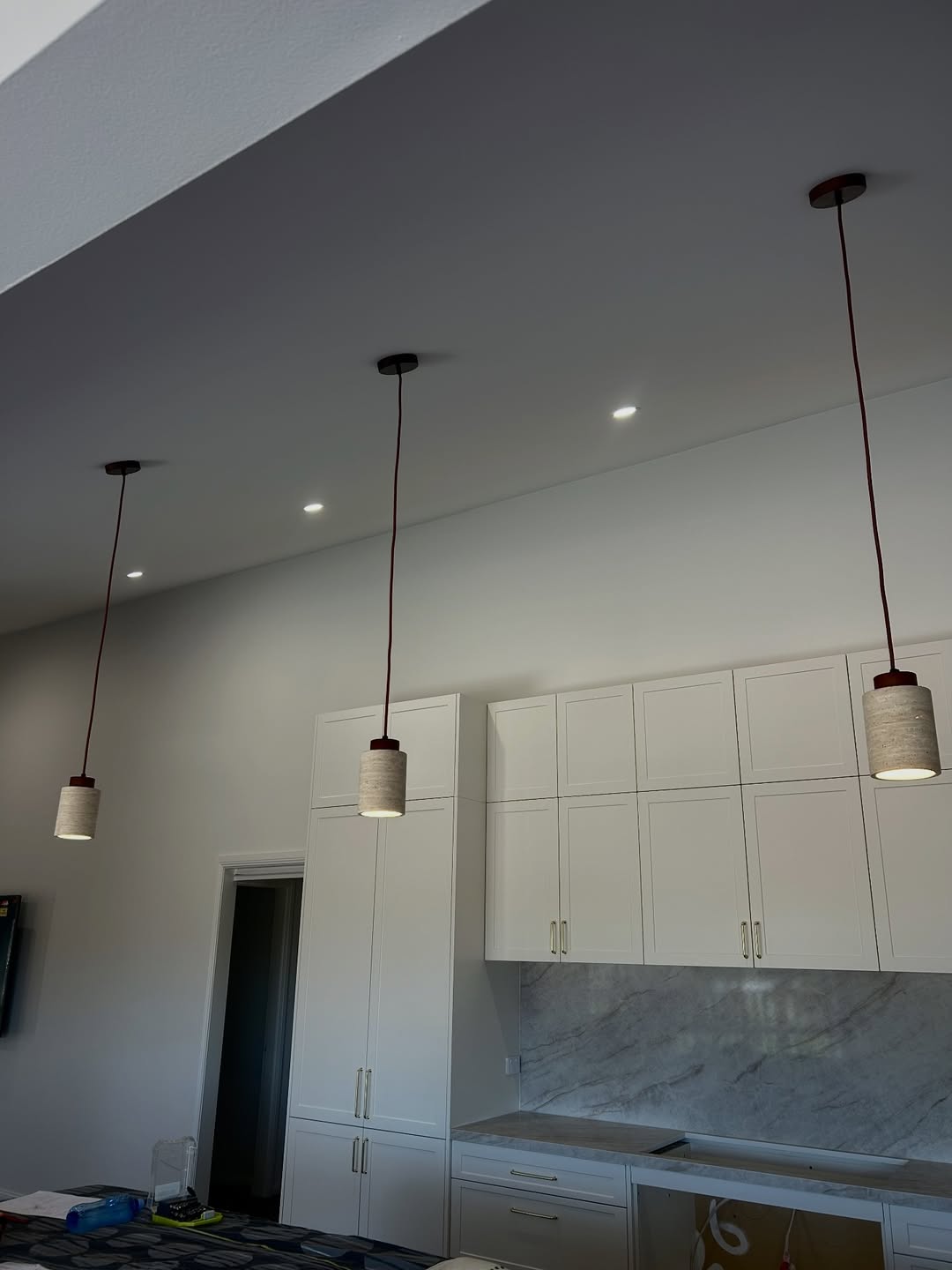Three red-cable concrete pendants in a white kitchen